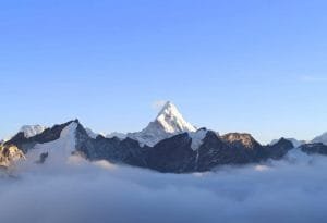 Everest Base Camp Trek via Salleri-Majestic snow-capped peak of Mount Ama Dablam rising above a thick sea of clouds under a clear blue sky in the Himalayas, Nepal.