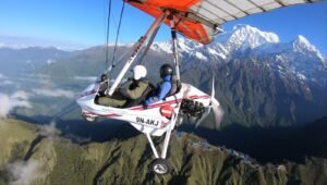 Ultralight Flight in Pokhara-Close-up of a tandem yellow and white ultralight aircraft soaring high above snow-capped mountain peaks.
